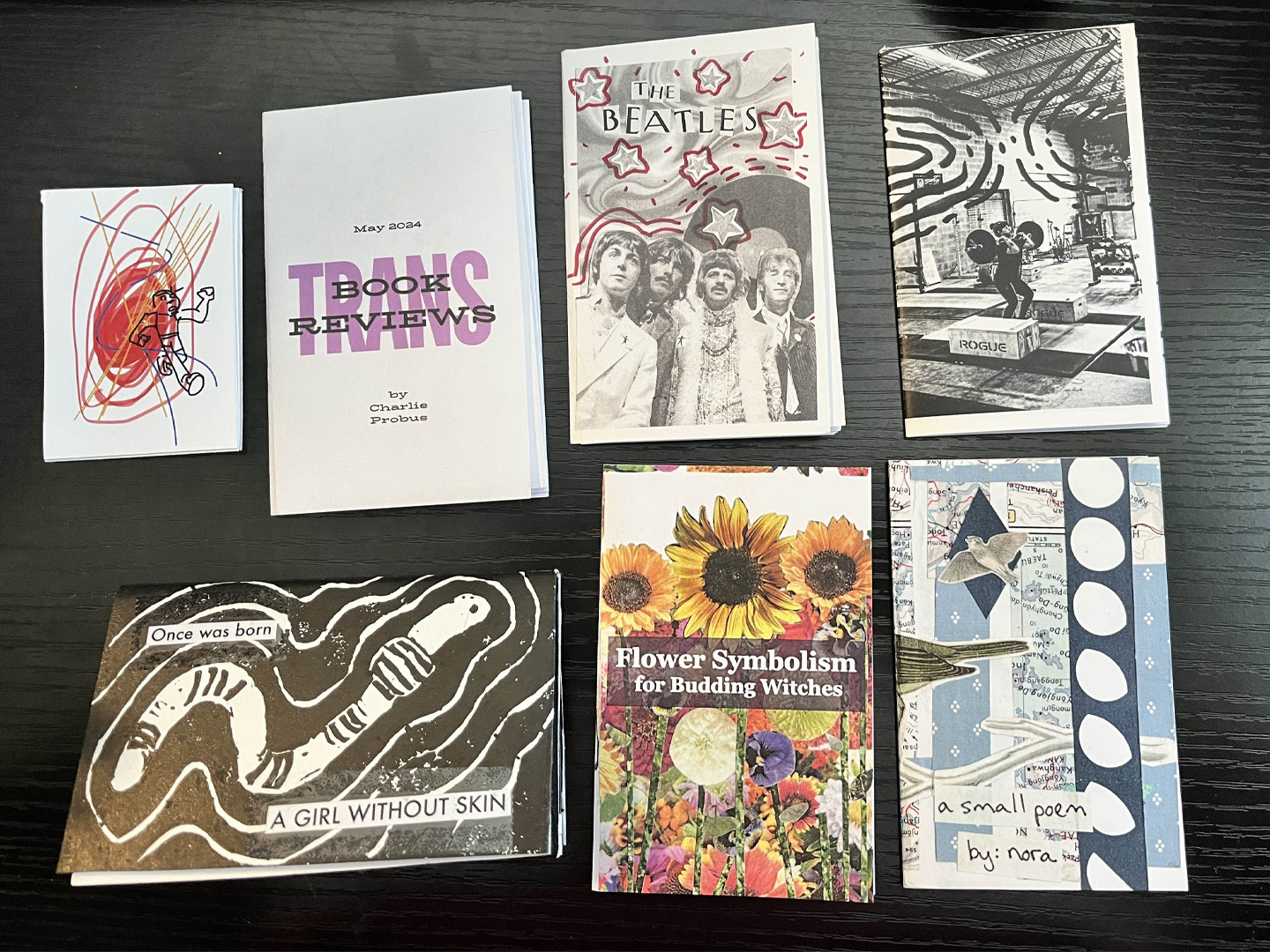 Seven mini-zines laid out on a table.